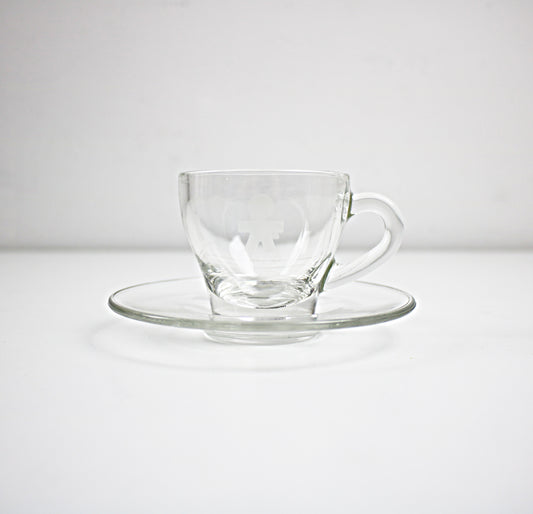 Clear glass cup and saucer set on a white background