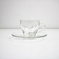 Clear glass cup and saucer set on a white background