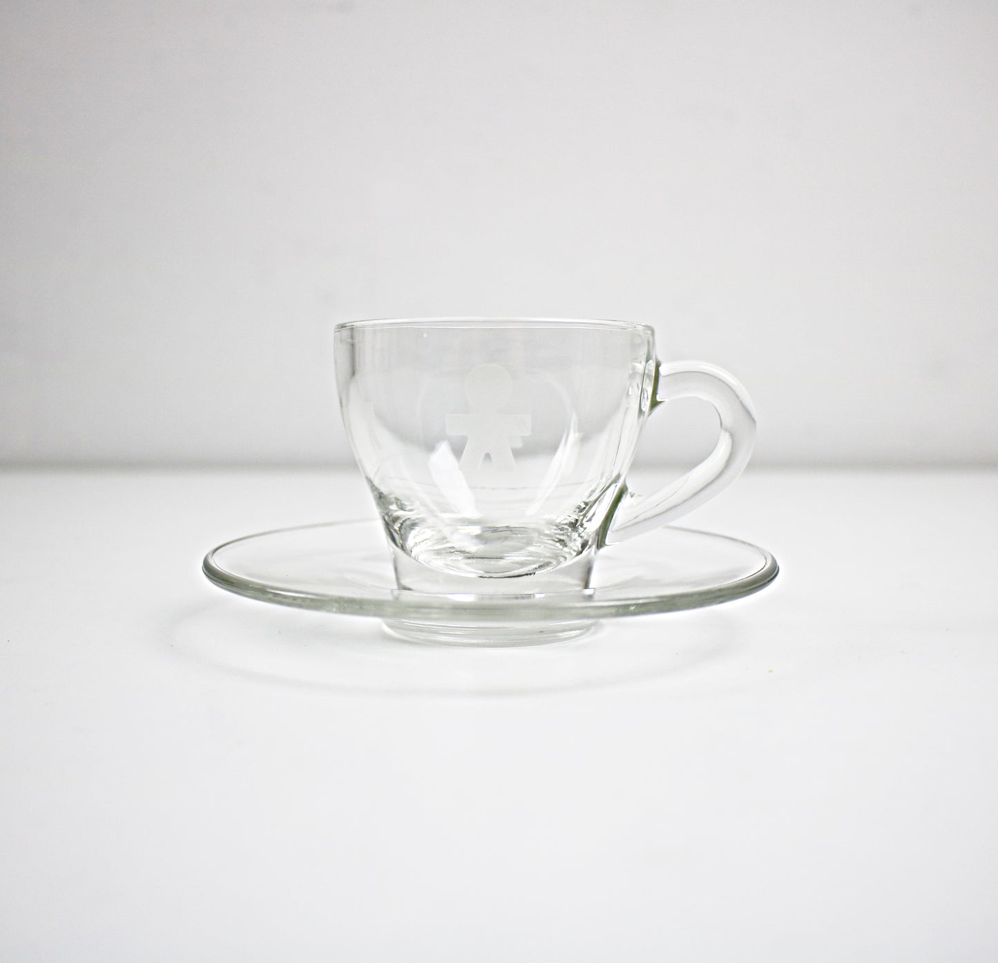 Clear glass cup and saucer set on a white background
