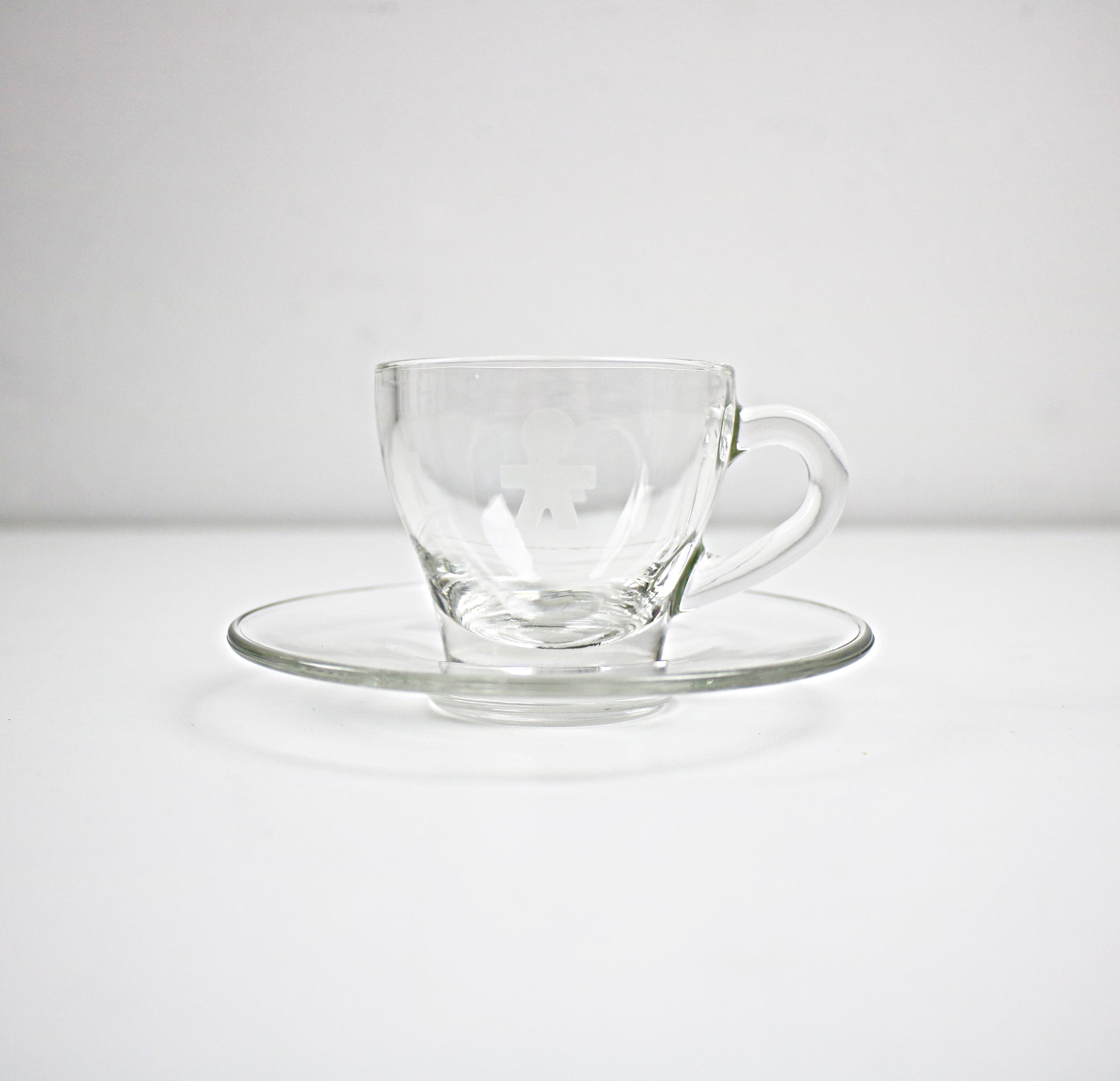 Clear glass cup and saucer set on a white background