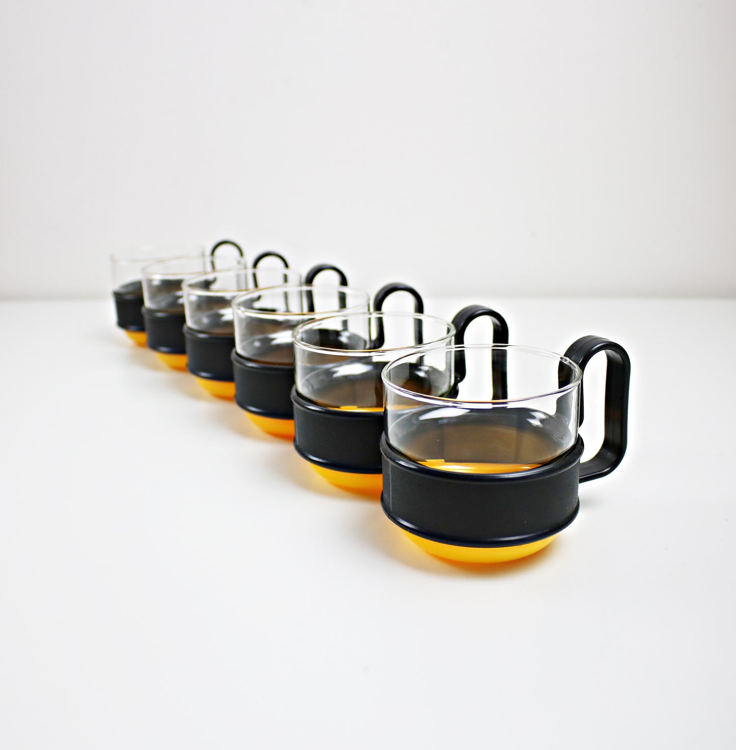 Pairs of modernist Pyrex Brasilia - glass and plastic cups - black and orange or black and yellow